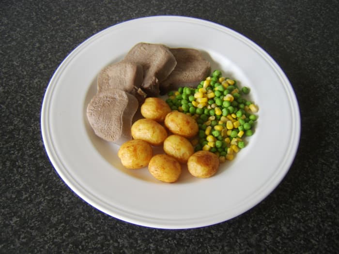 Still warm slices of ox tongue are served with pan roasted baby potatoes and a combination of peas and sweetcorn