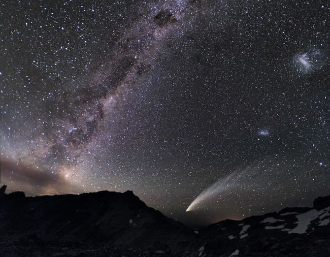 The Magellanic Clouds—two gauzy patches of light (at far right)—share the sky above the Patagonian Andes with a streaking comet and the luminous band of the Milky Way.