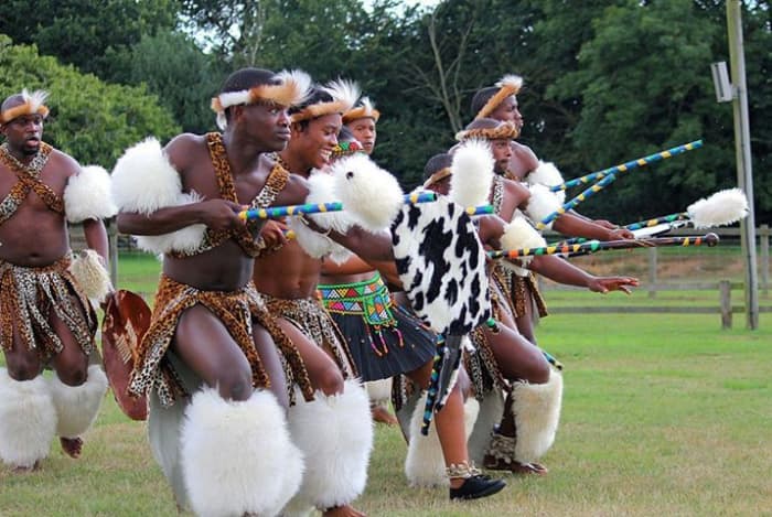 Zulu Dance Troupe performing a Zulu cultural Dance with one girl(partly obscured, in the line up