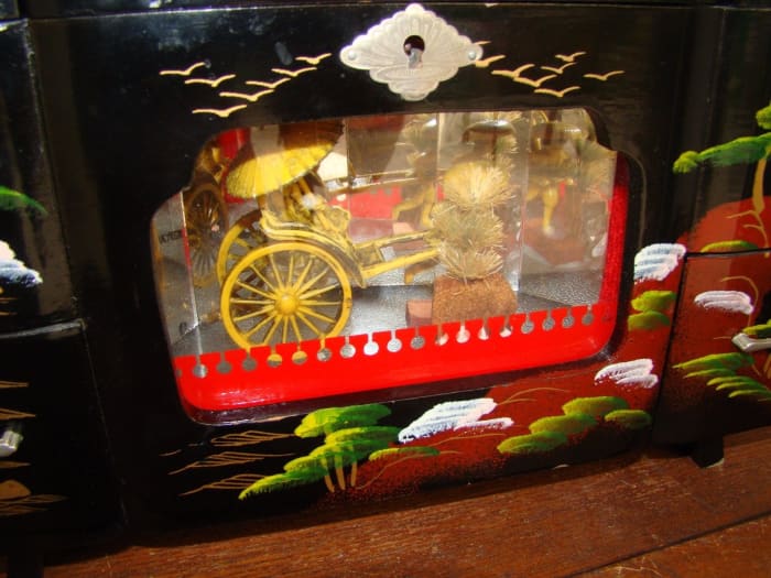 Wonderful vintage made in Japan large Jewelry Music box with a Oriental theme, and a Rickshaw that moves behind the glass to the Music being played. It is 13 inches long by 8 inches tall and 6 inches wide.