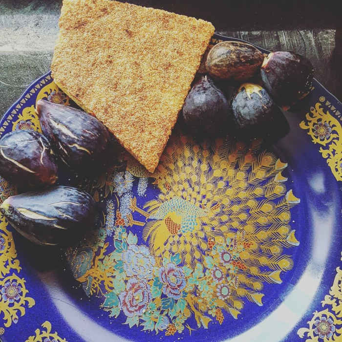 Fresh figs from Kenitra, Morocco, surround a slice of harsha. The plate is adorned with a peacock - a common design found on many platters.