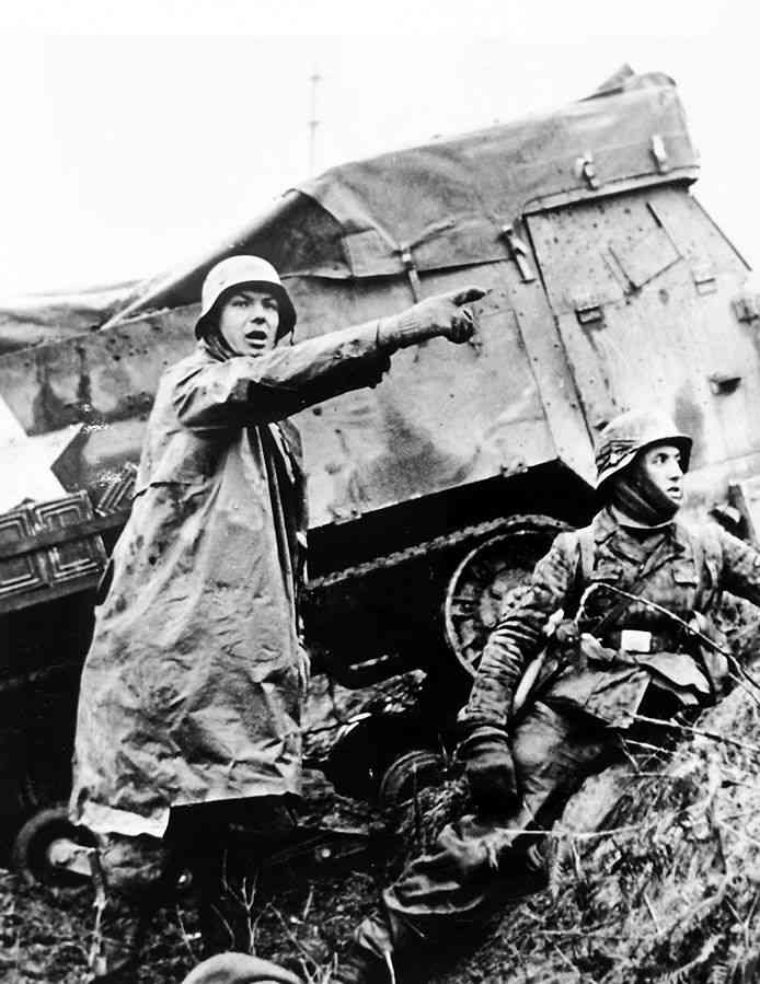 German troops advance past an abandoned American half-track early in the attack in the Ardennes forest December 1944.