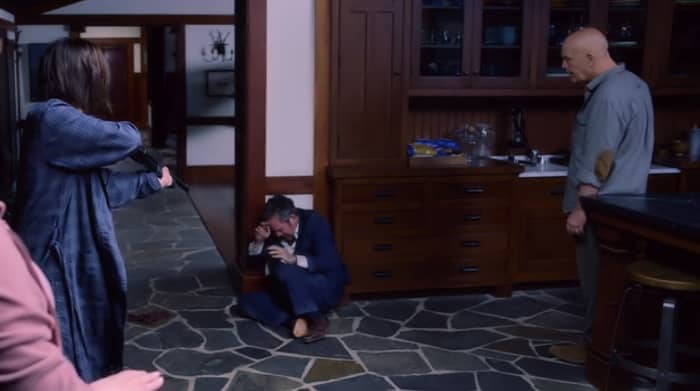 Malorie (Sandra Bullock) and Douglas (John Malkovich) grill Gary (Tom Hollander) at gunpoint when he arrives at the house in 'Bird Box' (2018), a Netflix Original.