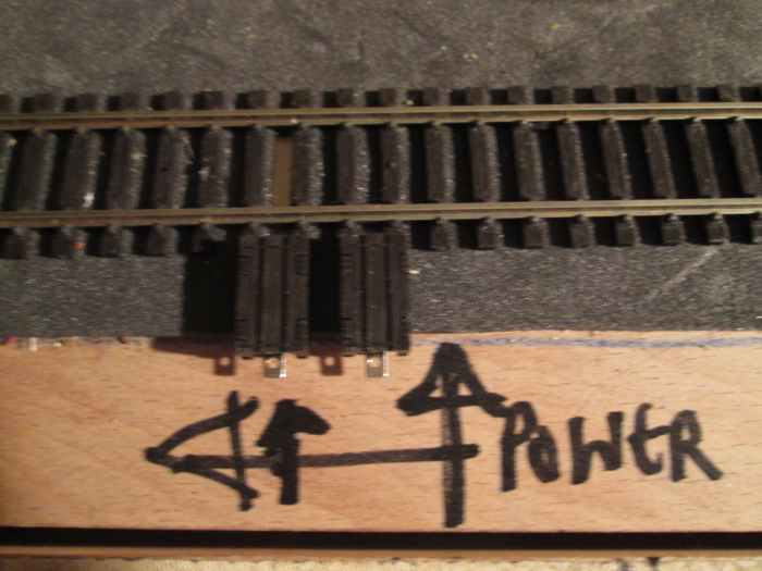 A pair of Peco power clips inserted to 'hold' the underside of the sleeper and rail. They're pulled around and over the edge of the sleeper to keep the power flow steady