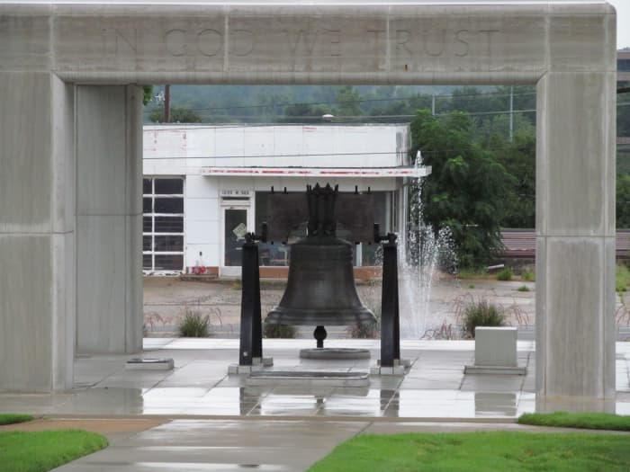 In God We Trust - Liberty bell sits in front of a closed gas station, under a marble cover...while the Little Rock Nine are out in the weather...