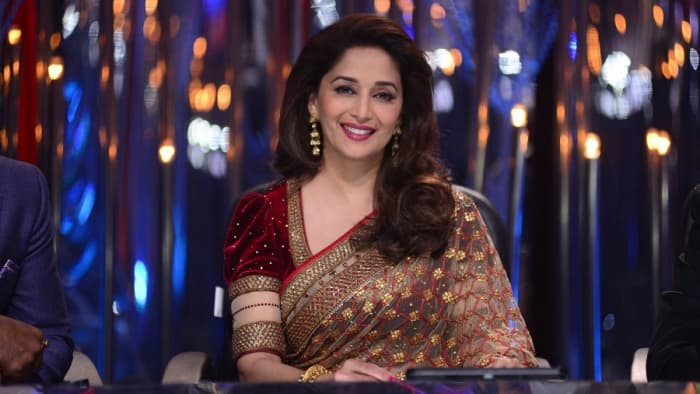 Madhuri Dixit looking beautiful in a maroon velvet blouse with puffed sleeves and a saree of beige net.
