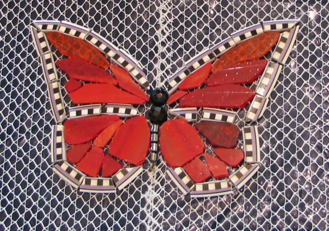 The edge is plate rim, red-orange stained glass, black faceted glass beads nipped in half, hematite bead body. Will be grouted with black grout.