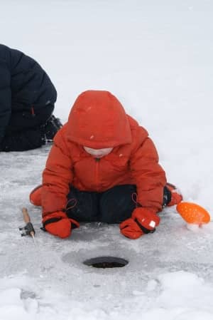A child checks for action beneath the surface while ice fishing at Upper Mississippi River National Wildlife and Fish Refuge.