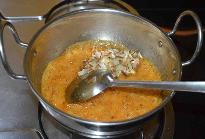 Step four: Add cardamom powder. Also, add roasted coconut pieces and cashew nut pieces. Mix well.