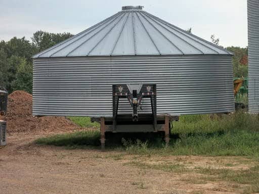 Iron supports were added to the sides of this trailer to stabilize this bin. For a bin which is much wider than your trailer and which you can haul safely in other respects, consider doing this.