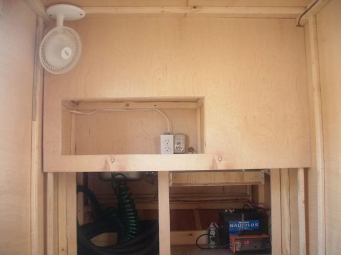 The back of the kitchen cabinet Shows the lower cabinet opening to the sleeping area. Also shows below the counter top and has access doors to storage and battery below.