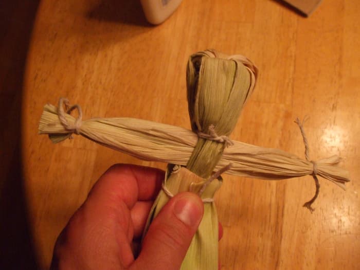 Tie the body below the arms. This photo shows extra skirt pieces being tied around the waist of a woman doll.