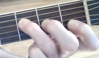 This is another way to get the F Major sound. Lay your first finger across the high E (first string), but do not push down. The string is being muted, you should hear a non-pitched sound, more of a scraping sound on the note