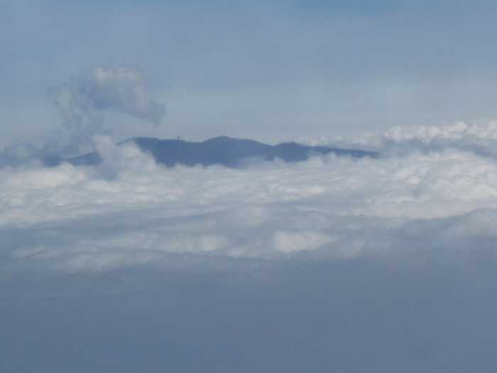 Summit of Mauna Kea or Mauna Loa poking through clouds as seen from an airplane
