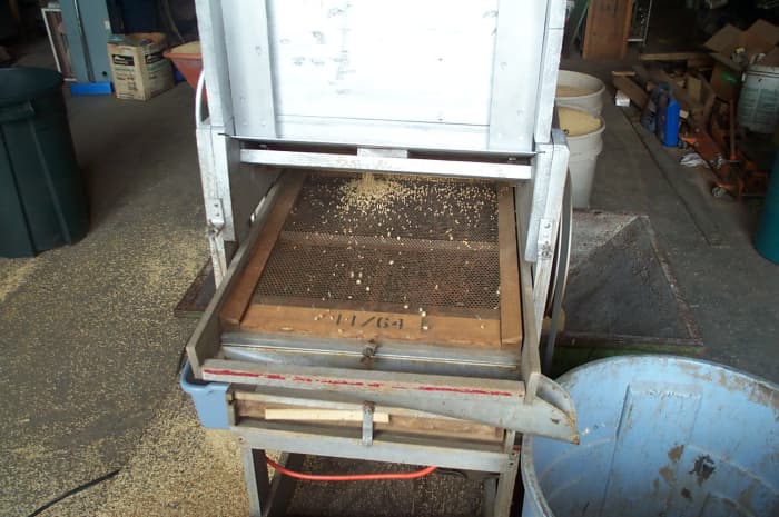 The fan mill electric motor is started, and the hopper is adjusted to let only a trickle of grain pass through.