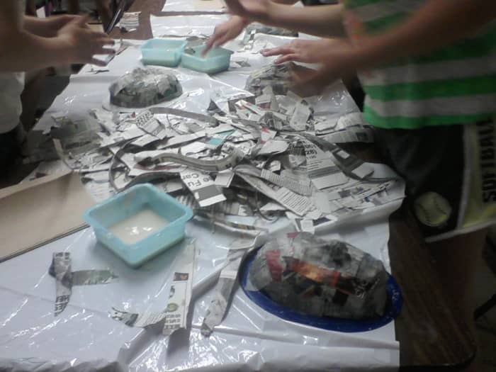 Newspaper is torn into strips, then dipped into the paper mache paste and layered onto the mold