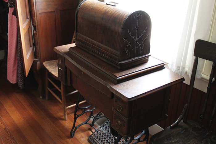This is a vintage treadle machine with another machine and case on top. Probably a Singer model 127 portable hand crank.