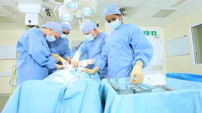 Multi ethnic medical team performing operation in hospital operating theater