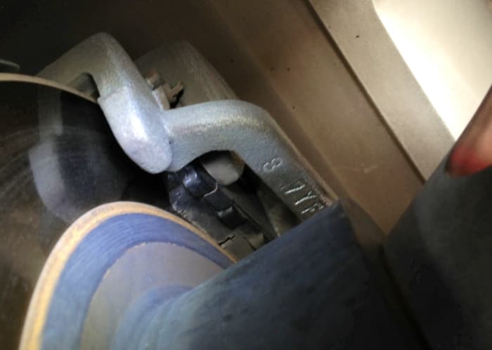 Material left between the brake disc and backplate of the pad is crucial. The groove cut into pads for venting heat and gases also helps gauge how much is left.