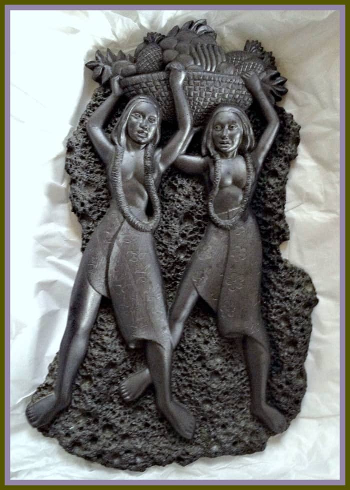 A vintage black lava Coco Joe wall décor plaque depicting two Hawaiian Hula Girls with a bowl of pineapples above their heads. It measures approximately 12" long and 7" at its widest. It weighs 2 lbs 5.0 oz. Makes a great addition to your tiki bar.