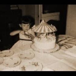 That's me, at the age of four or five. My mom took the picture, or my dad... not sure which one, really. Mom used to buy lovely birthday cakes from the bakery. This one was a carousel with animal figurines on it.