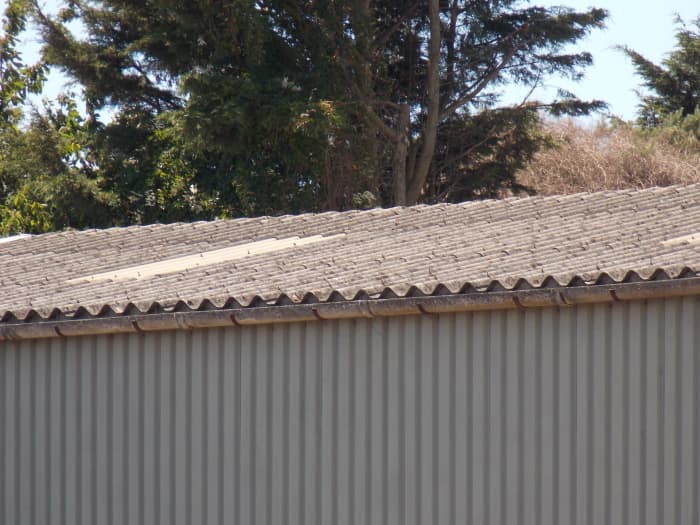 An example of corrugated asbestos roofing sheets on a factory roof, which are make from asbestos cement.