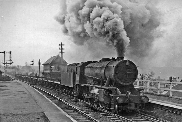 At the easternmost end of the Cleveland Railway, unidentified Riddles' War Department 2-8-0 with empty bolster wagons heads to Skinningrove Works for coil load. The brake van can be seen at the left below the bracket signal and gantry beyond