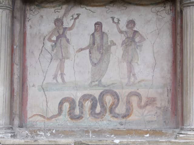 VI.15.1 Pompeii. December 2006. Household lararium in service area. Painting of serpent, (Agathodemone), garlands and three figures. The household gods (Lares) are either side of the guardian spirit (genius loci) of the house.