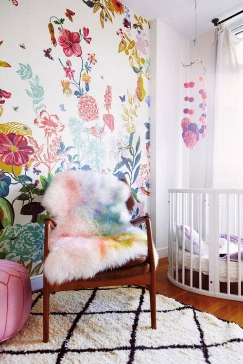 The bright colors inspire the accessories with the watercolor sheepskin & pom-pom mobile over the crib.