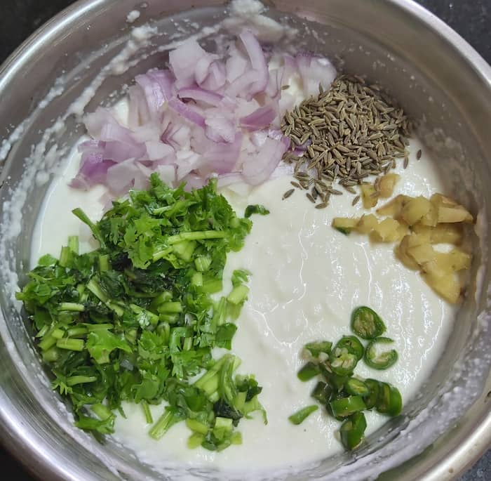 To this batter, add 1-2 finely chopped onions, 1 teaspoon cumin seeds, 2-3 tablespoons of finely chopped fresh coriander leaves, 1-2 finely chopped green chilies, 1 inch long finely chopped fresh ginger.