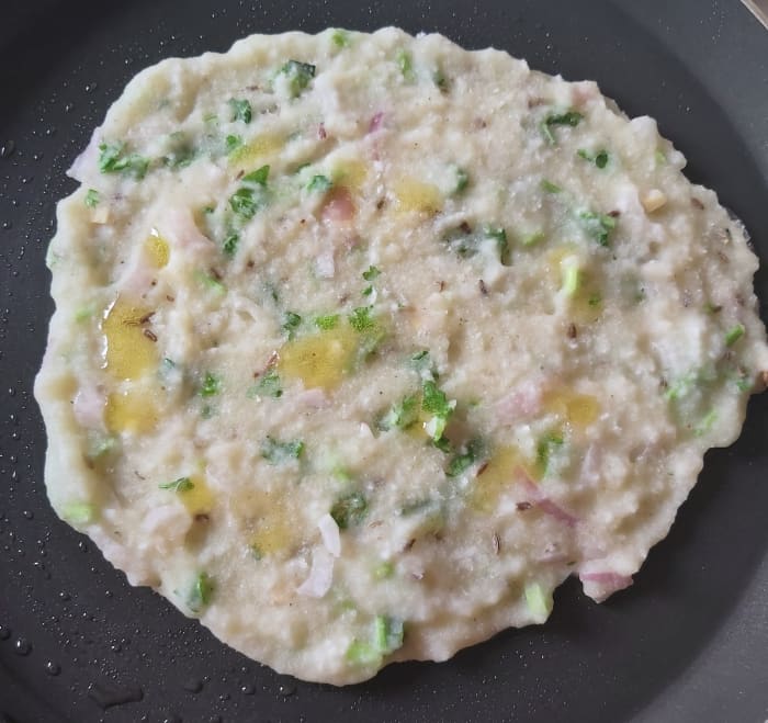 Sprinkle some drops of ghee on rotti. Cover and cook for a minute in a medium flame till above side cooked properly.