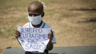 Oliver Sanchez, a cancer patient from Venezuela. He and his family couldnt find the medicines needed for his treatment. He's holding a sign that reads "I want to get better - Peace - Health" Oliver passed away due to the lack of essential treatments
