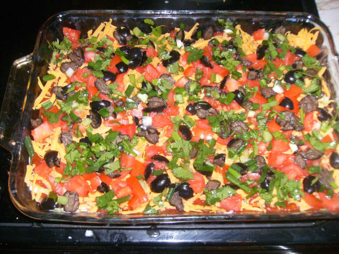 The tomatoes, green onions, and cilantro on top of the cheese and black olives make the dip quite attractive.