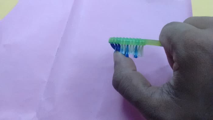 And then using our thumb gently rub the bristles of the brush and allow the spray to settle on the paper.