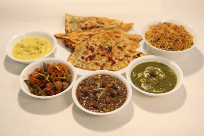 A Thali (pictured above), typically served in a round style or round plate, consists of choices of vegetable dishes along with buttered Indian bread and other condiments.