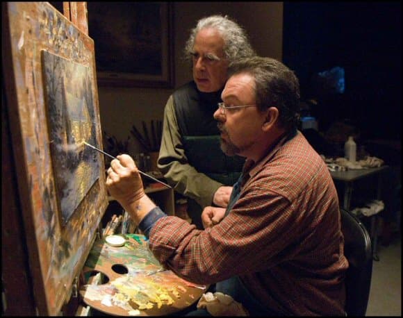 Movie Director Michael Campus watches Thomas Kinkade working on his painting "The Christmas Cottage"