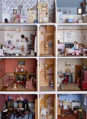 A vintage style 3-storey dollhouse with a central wooden spiral staircase, a parlour, fireplace, kitchen, bedrooms and bathroom.
