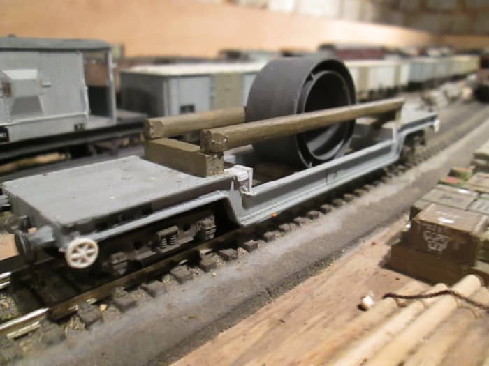 A ready-to-run Bogie Well wagon that started off as GW, modified, with brake wheels added from a plastic sprue and real wood bolsters to hold engineering parts (plastic Sellotape reel centre, painted engineering grey)