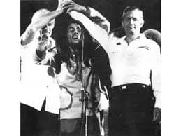 Bob Marley unite two warring factions JLP and PNP at his 1978 One Love Peace Concert. This is after they tried to kill him. Symbolic of uniting communism and capitalism.