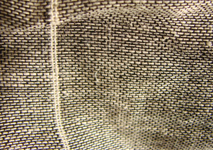 This close up shows the vertical threads, called the warp and the horizontal threads called the weft.
