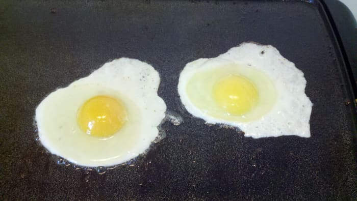 One of our eggs frying on the left next to a store one on the right. See the difference in yolk color?