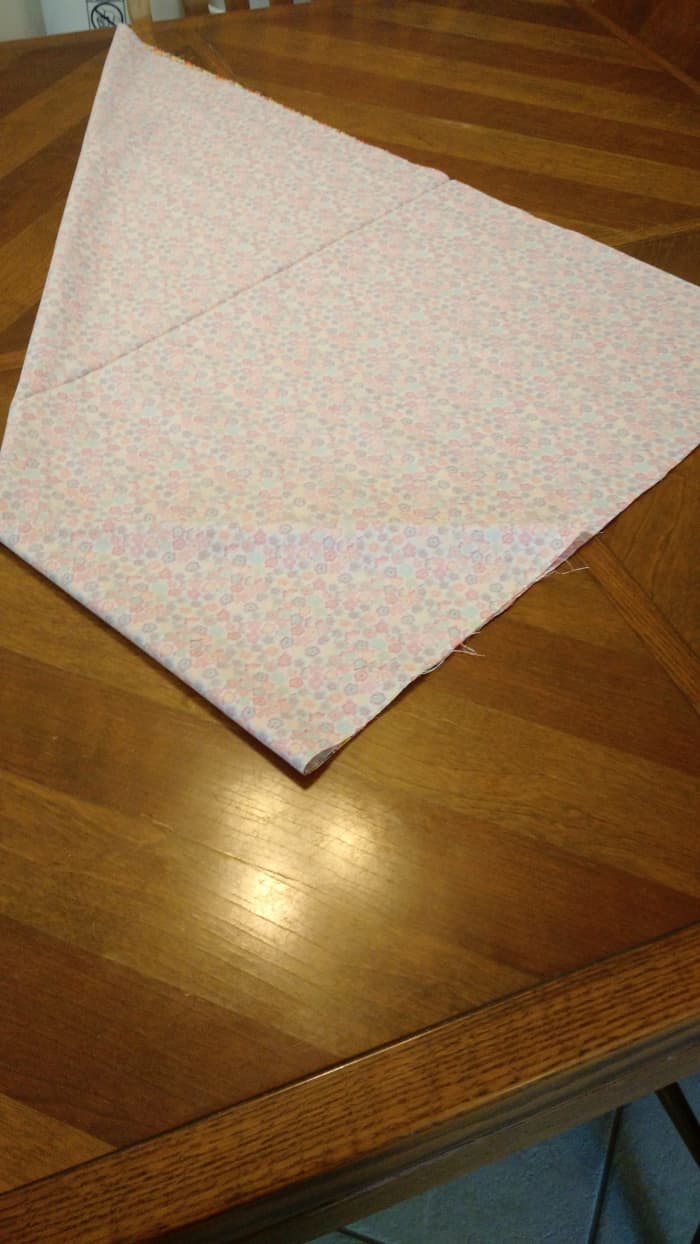 Fold the corner of the fabric about half way to the top and then tie a knot. Then repeat on the other side.
