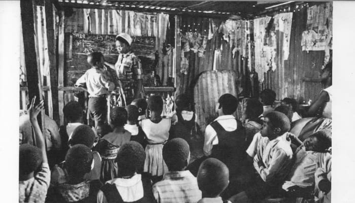 African children attending classes in any available structure, a tin shack, because of the shortage of school building. Parents and the township resident have to raise half the cost