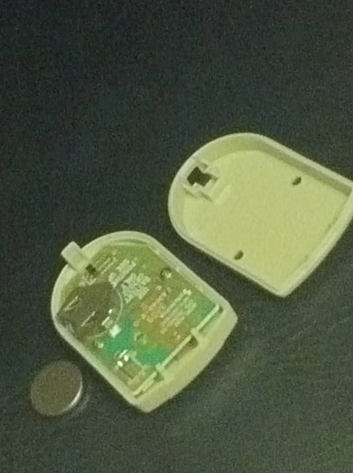 The garage door sensor consists of a simple circuit board, the two halves of its case, and a flat battery.
