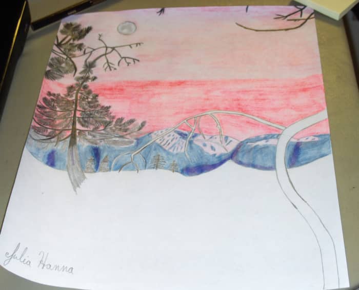 Here I am beginning to fill in the silhouette of the pine trees and the mountains with a black colored pencil.