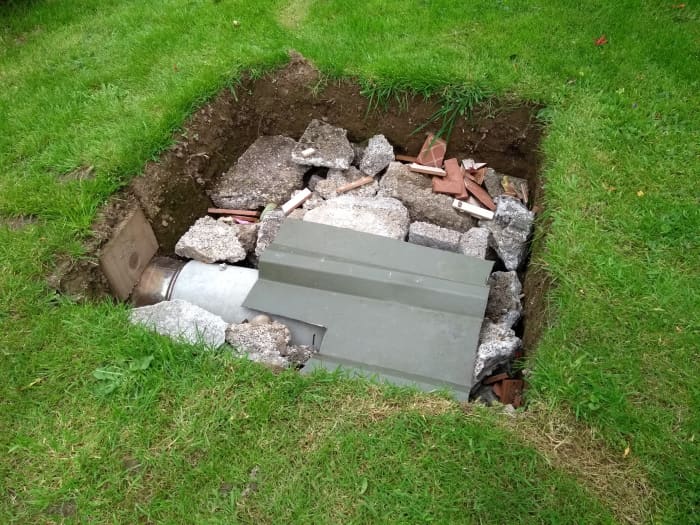 A waste piece of galvanized cladding stops any clay from clogging the outlet of the pipe.