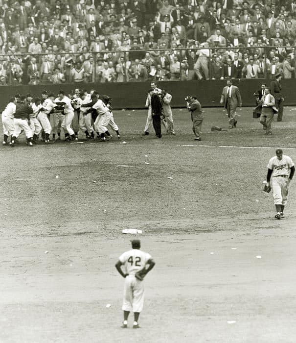 A rarely seen angle: The Giants mob Thomson as a dejected Ralph Branca starts the long walk to the visitors' locker room in centerfield. Jackie Robinson stands in shock.