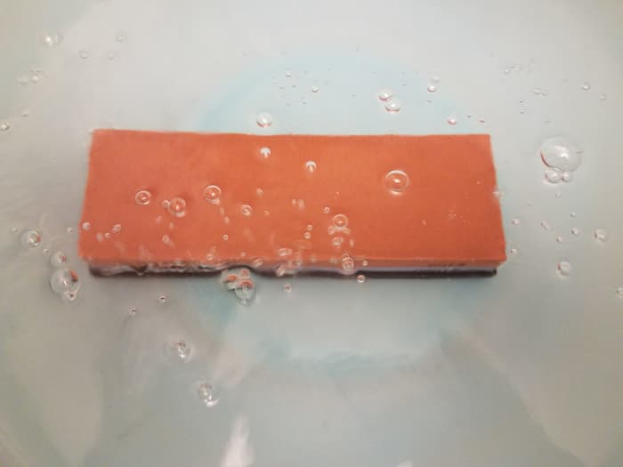 Soaking a stone for five minutes to saturate with water.