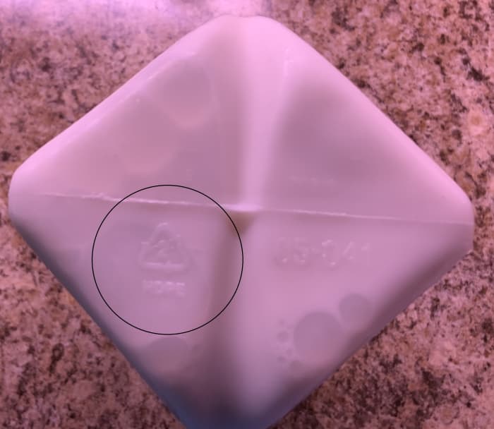 Bottom of a half gallon of milk that has a "2" inside a triangle with "HDPE" next to the triangle. This is recyclable High density polyethylene plastic.