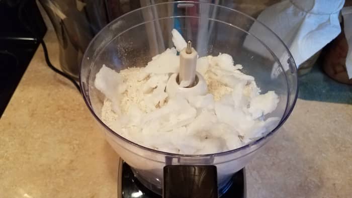Then I pull my coconut oil out of the freezer and break it all into small pieces. I add that to my processor and process that in as well.